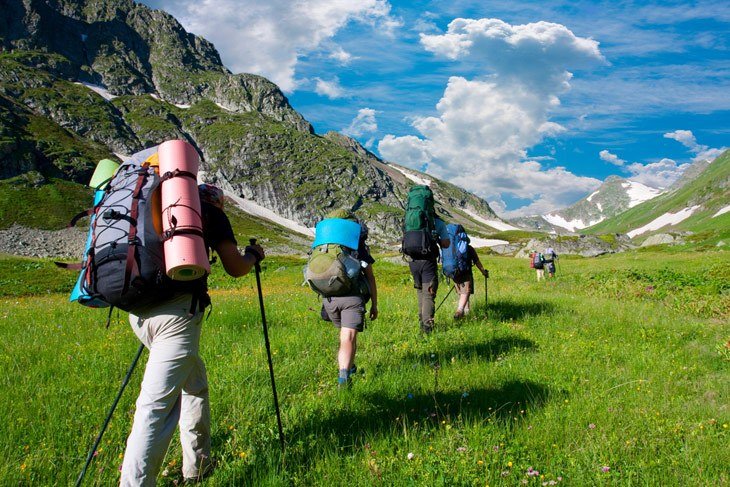 Group Of Hikers With Backpacks In Mountains