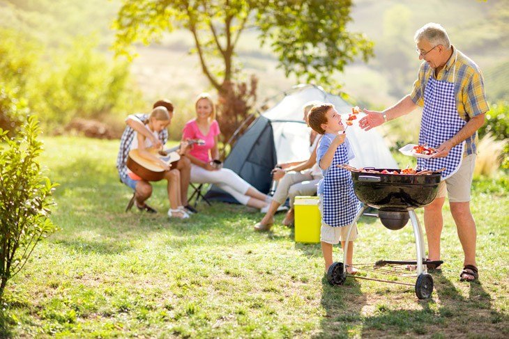 Grandfather And Grandson Making Barbecue For Family On Camping