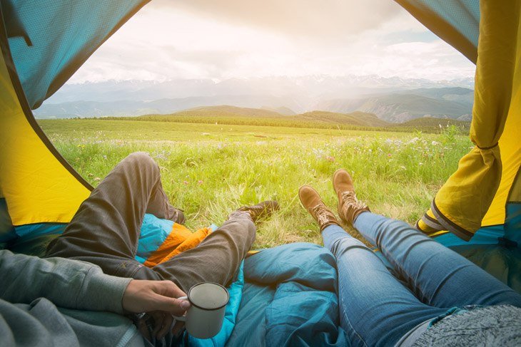 Two People Lying In A Camping Tent With A View Of Mountains